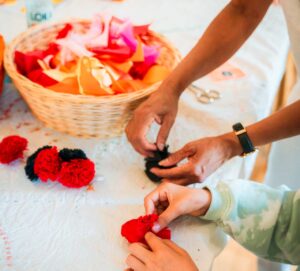 Två par händer pysslar med mexikanska pappersblommor.
