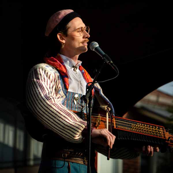 Artisten Fredy Clue spelar nyckelharpa och sjunger på en scen